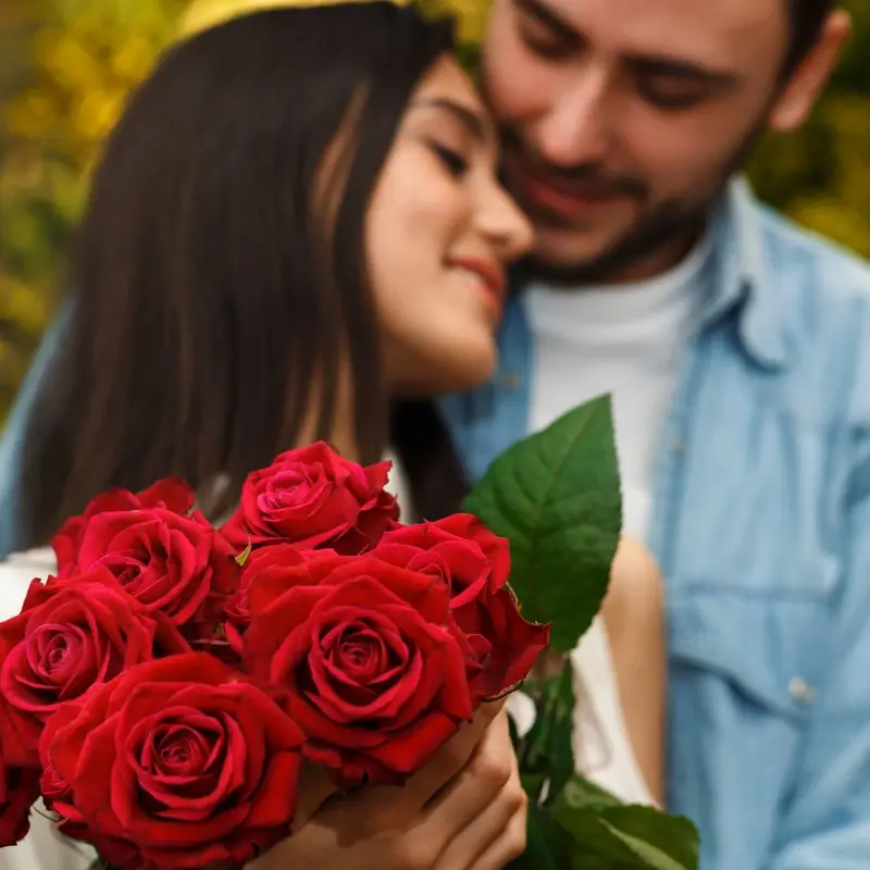 En kvinna med Alla Hjärtans dag rosor är väldigt nöjd när hon blir kramad av sin pojkvän som precis givit henne röda rosor på denna speciella dag av romantik.